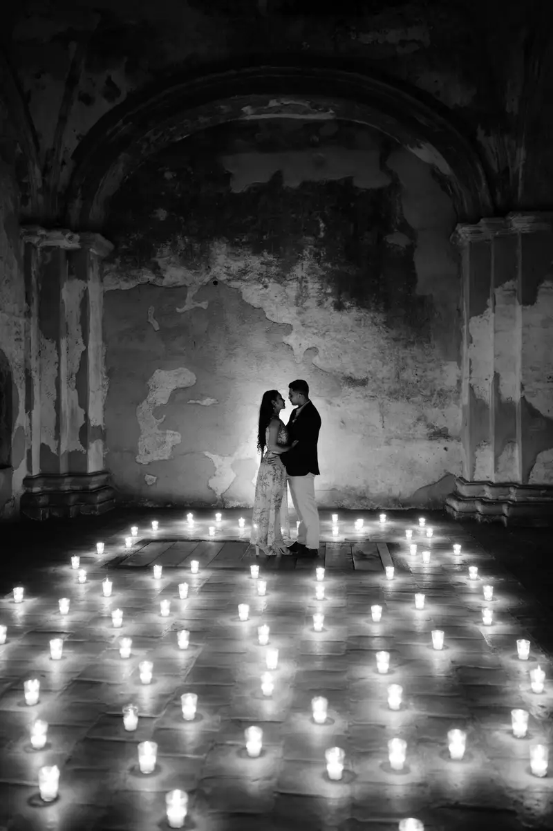 La pareja de lejos en el ábside de una iglesia colonial, rodeada de velas