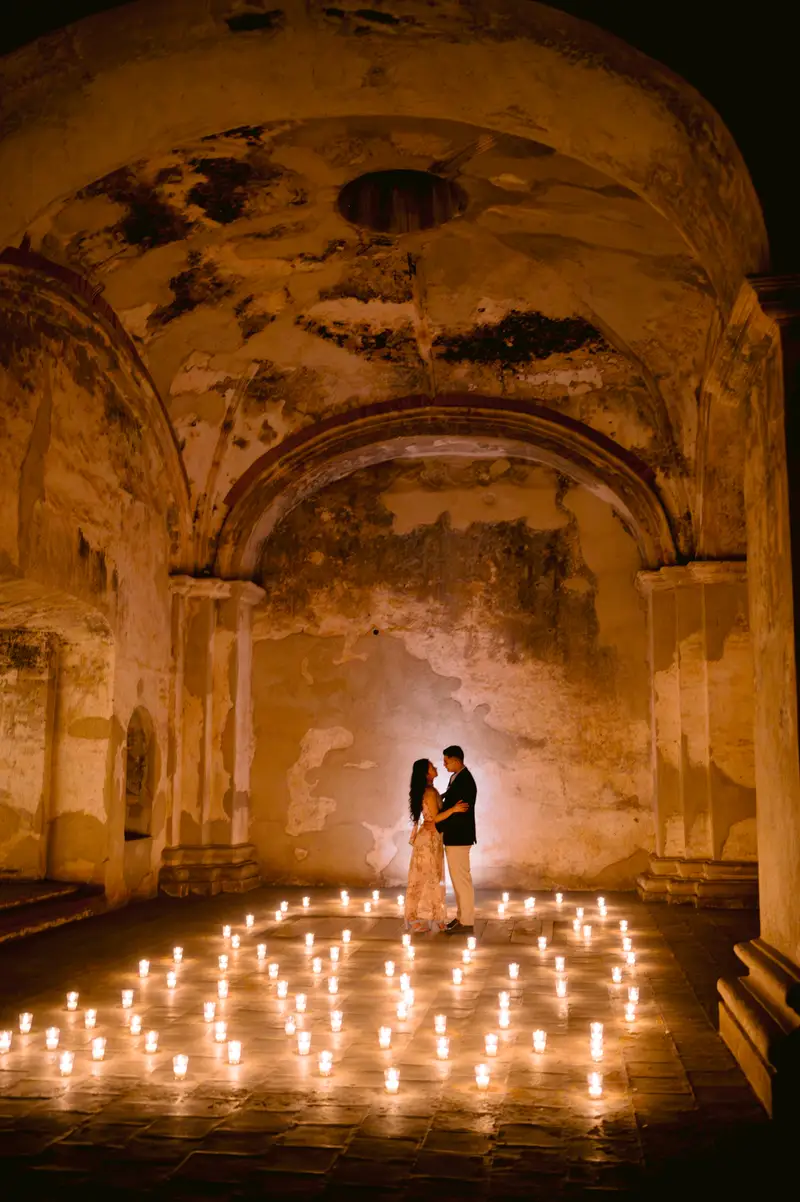 La pareja bajo una bóveda colonial iluminada con velas